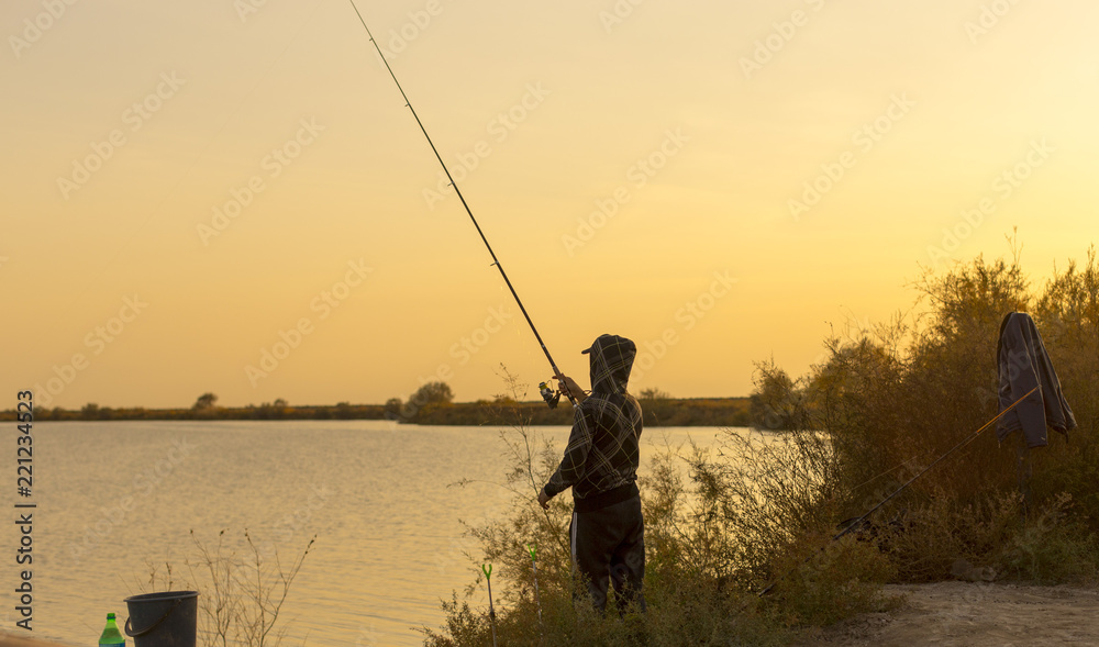 man is fishing at sunset