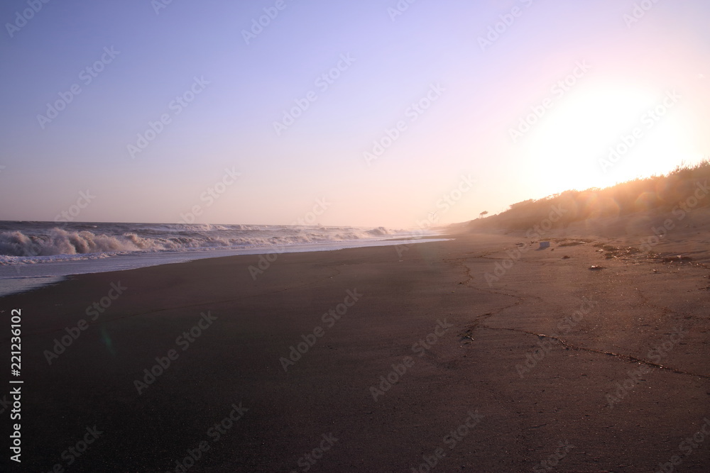 夕暮れ時の日本海の荒波と砂浜