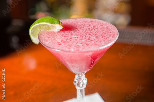 A pink cocktail with a slice of lime