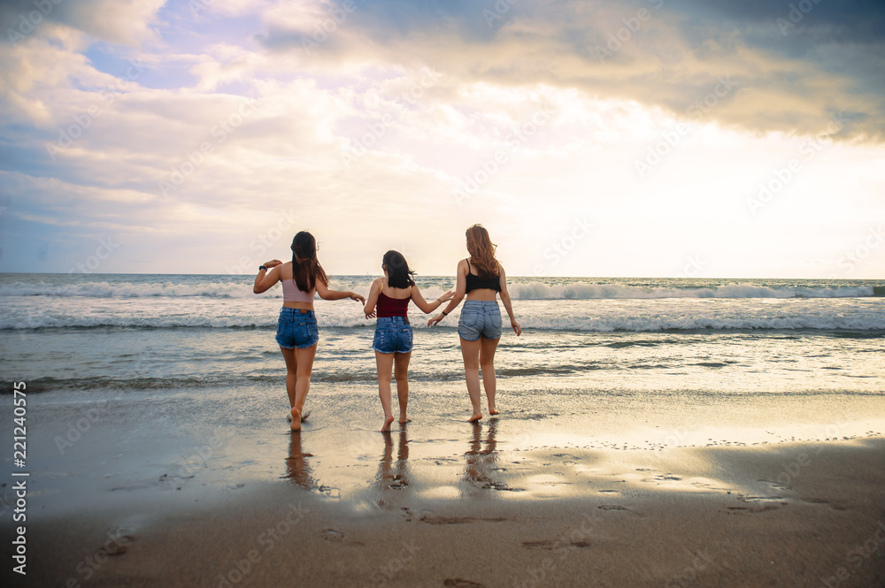 young women friends or sisters playing together in the beach on sunset light having fun enjoying summer holidays trip in girlfriends love and friendship concept