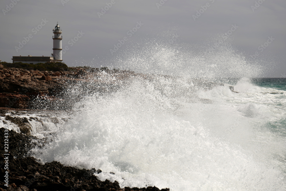 Waves crashing over rocks at lighthouse