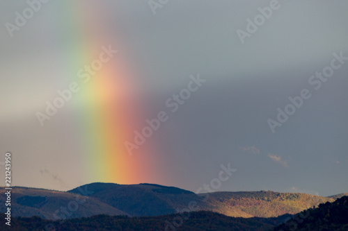 Beautiful and surreal view of part of a rainbow over some hills