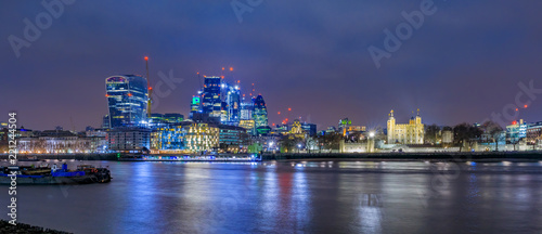 London city skyline at night with skyscrapers against cloudy skies and the Tower of London in England UK