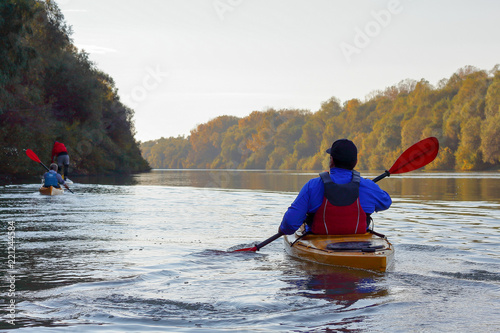 A guy in a yellow kayak rowing in the autumnal river Danube on a calm autumn day © watcherfox