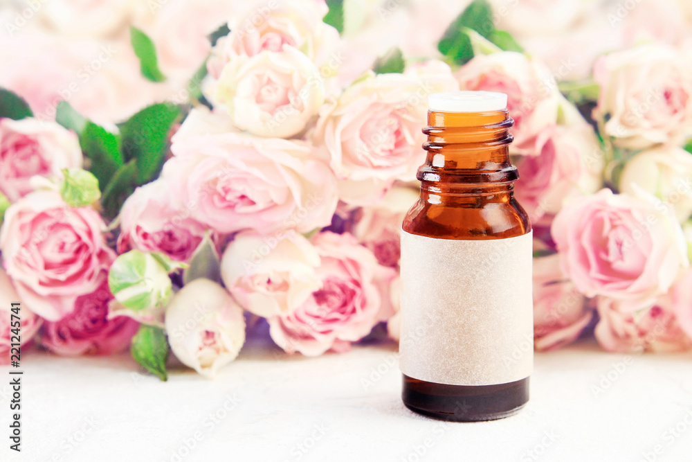 Glass bottle essential oil empty craft label on table with roses pink soft blurred background. Aromatherapy spa product Glass bottle essential oil empty craft label on table with roses pink soft blurred background. Aromatherapy spa product