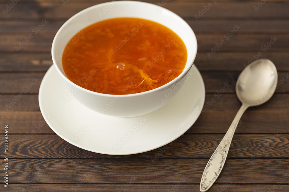 Chicken soup with vegetables and herbs in a white bowl on a wooden table Chicken soup with vegetables and herbs in a white bowl on a wooden table
