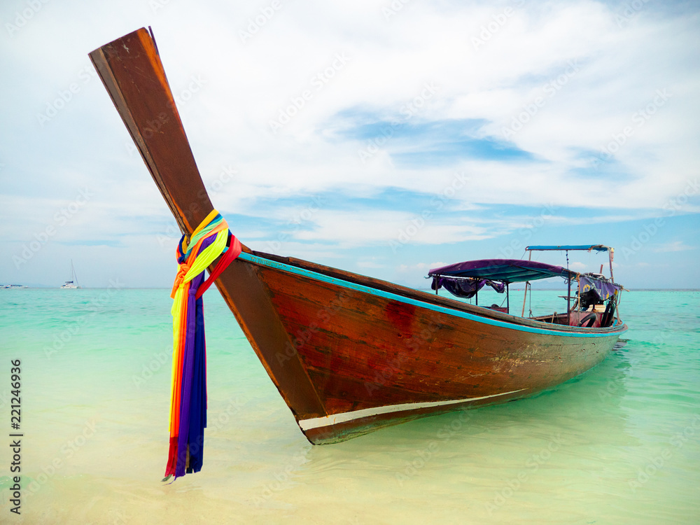Traditional Long boat with colorful ribbons on Phi Phi Island near Phuket in Thailand on turquoise water with white clouds against blue sky Traditional Long boat with colorful ribbons on Phi Phi Island near Phuket in Thailand on turquoise water with white clouds against blue sky