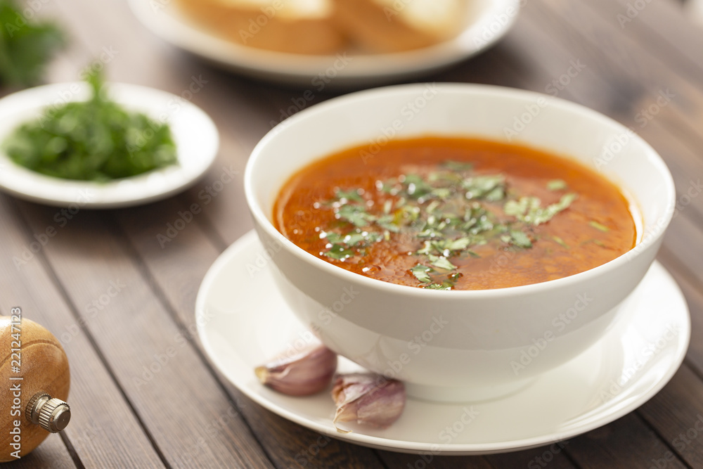 Chicken soup with vegetables and herbs in a white bowl on a wooden table Chicken soup with vegetables and herbs in a white bowl on a wooden table