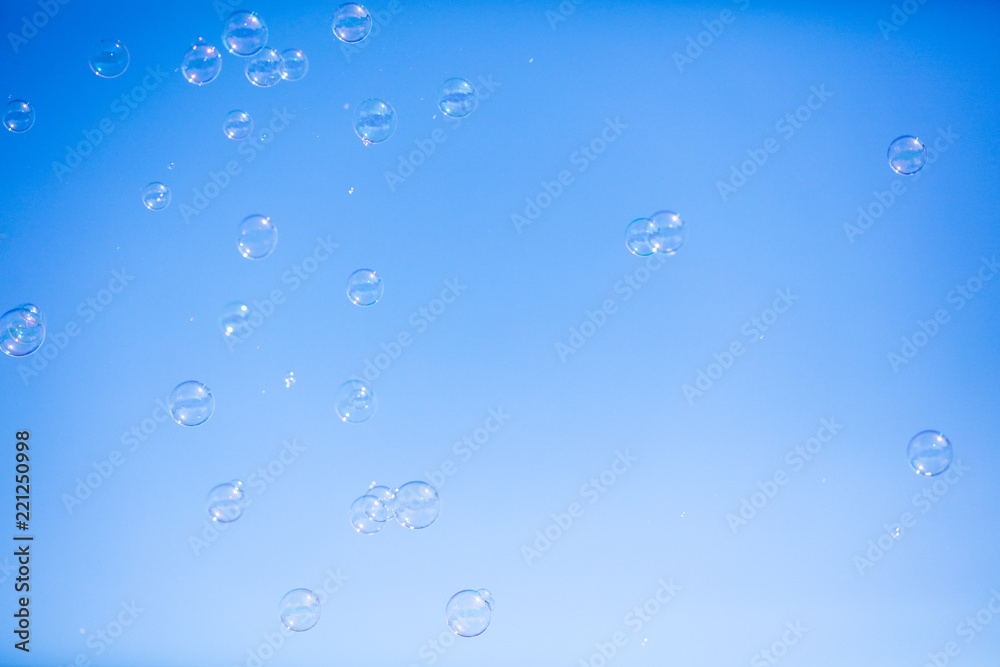 Soap bubbles in flight against the blue sky