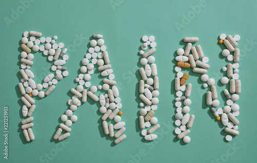 Painkiller pills spelling out Pain on green background