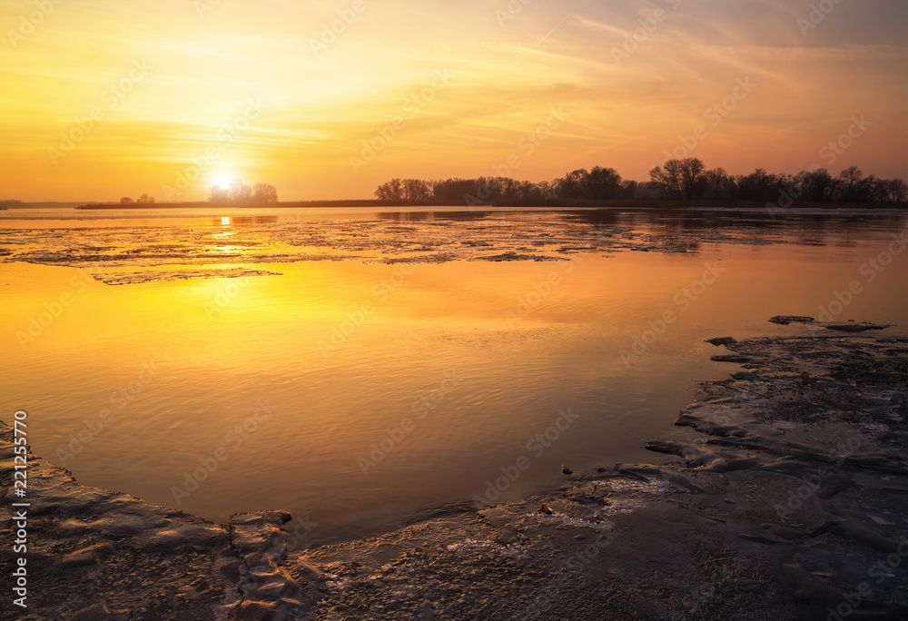 Beautiful colorful winter landscape with frozen lake and sunset sky.