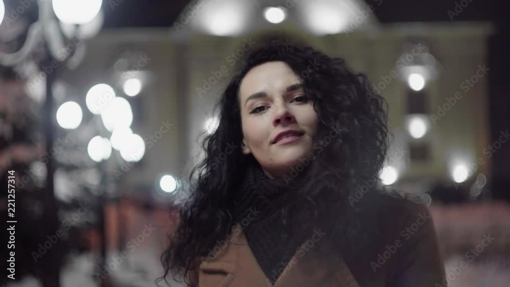 Beautiful attractive young woman standing in a city street and winking at a camera Beautiful attractive young woman standing in a city street and winking at a camera