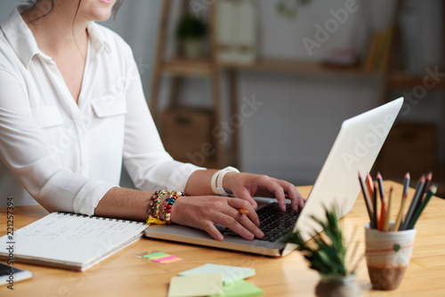 Cropped image of woman taking online class and writing down details