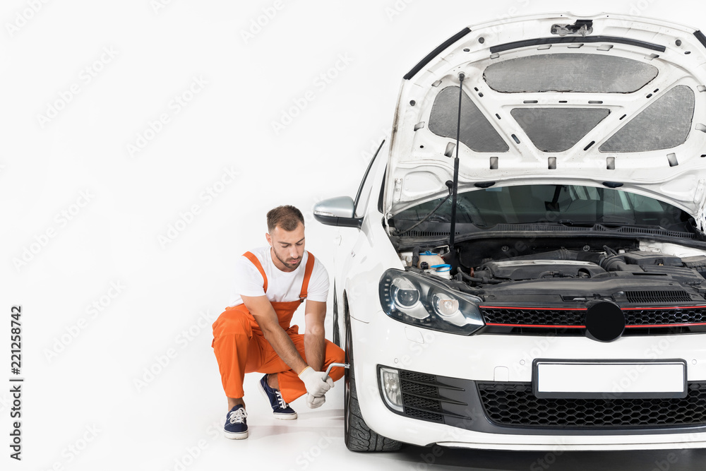 auto mechanic changing car tire with open hood on foreground auto mechanic changing car tire with open hood on foreground