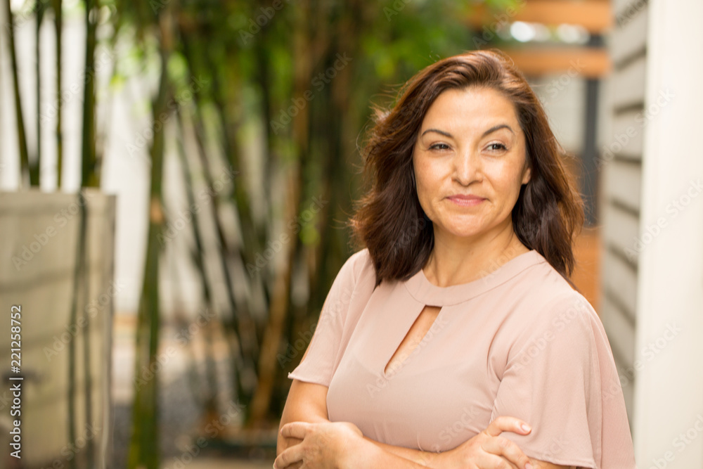 Happy Hispnaic woman smiling and standing outside.