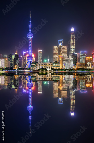 Blick auf die urbane Skyline von Shanghai bei Nacht mit Reflektionen im Huangpu Fluss, China