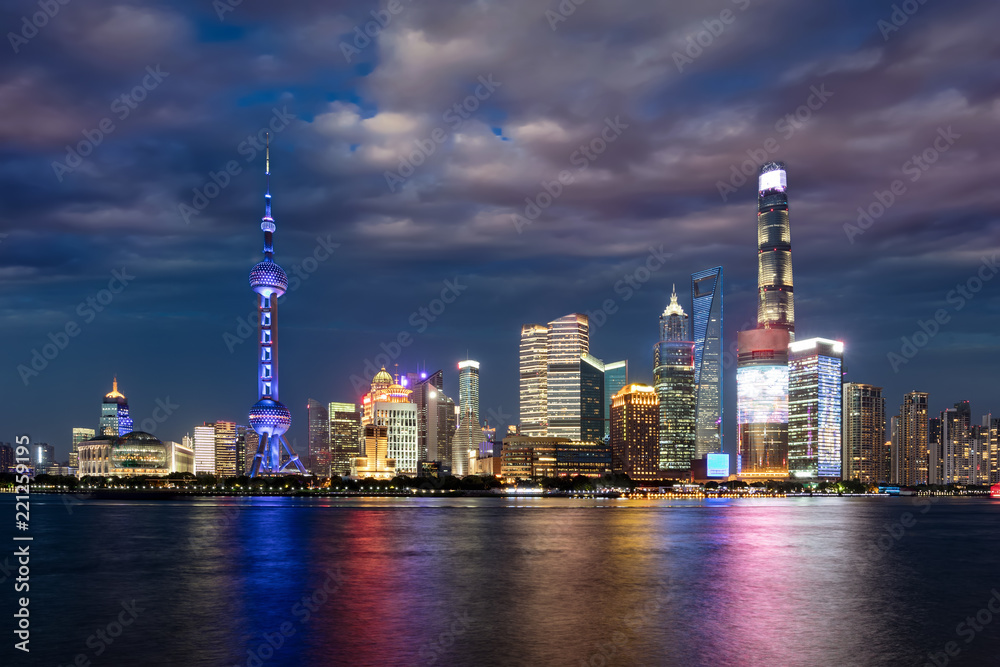 Die hell beleuchtete Skyline von Shanghai am Abend mit bewölktem Himmel, China