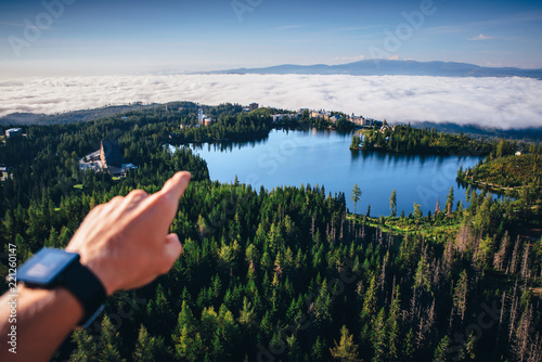 Hand pointing to the beautiful nature on blue lake and mist in the valley photo