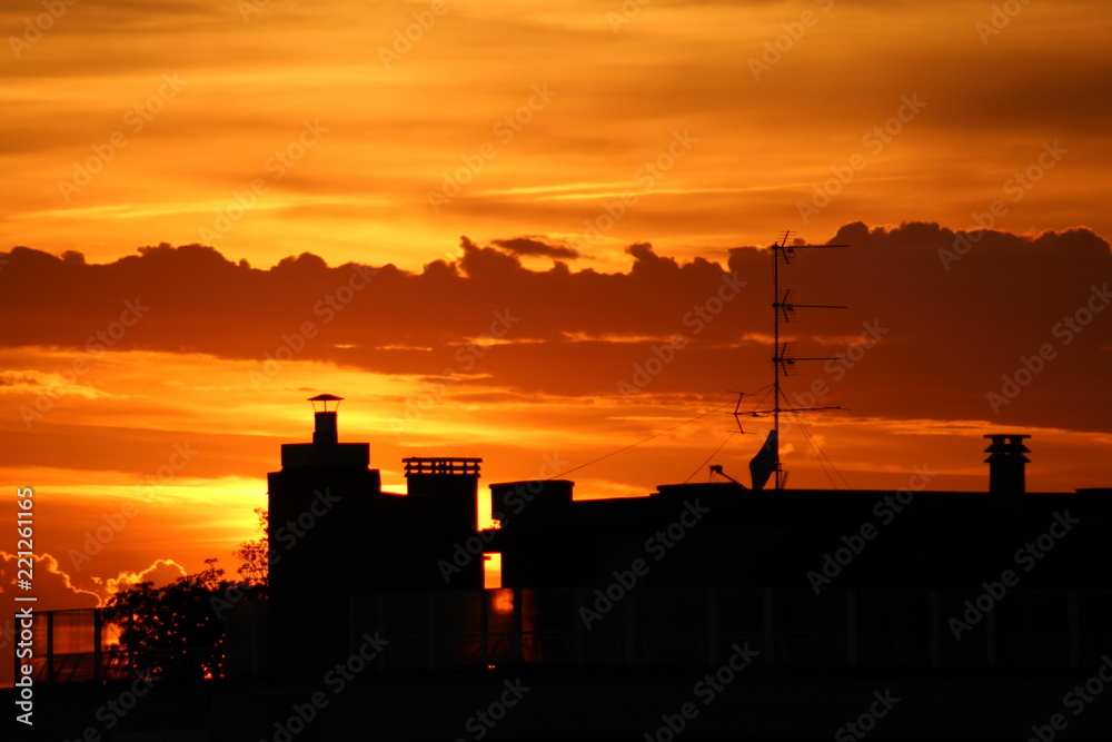Urban sunset: sun going down with orange sky behind city buildings