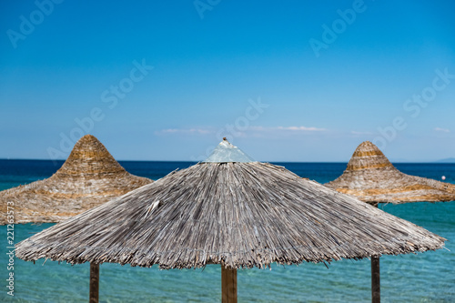 Straw covered umbrella on the beach with turquoise water in the background
