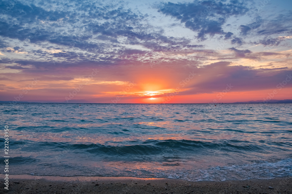 Sun setting over the horizon reflecting the sea with colorful sky above. Nature, hope, relaxation background
