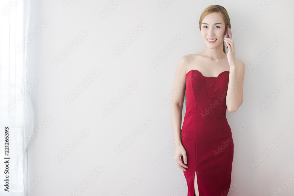 Portrait of a happy young Asian woman holding mobile phone while standing and looking to camera Portrait of a happy young Asian woman holding mobile phone while standing and looking to camera