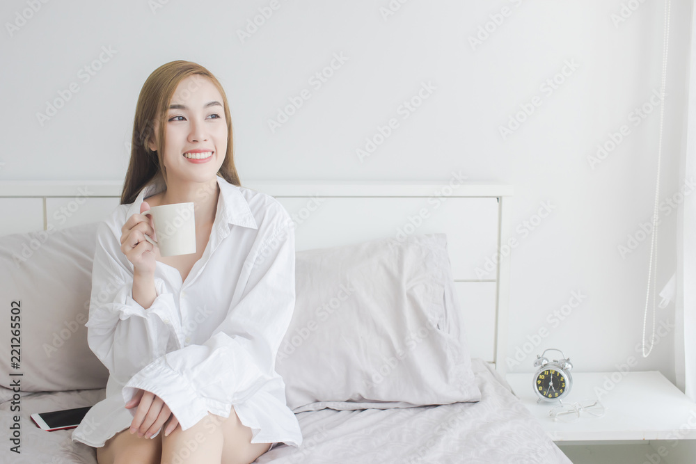beautiful Asian women in white shirt drinking coffee and smile in her bed beautiful Asian women in white shirt drinking coffee and smile in her bed