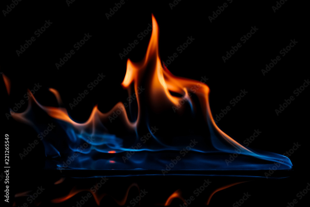 Fototapeta premium close up view of burning orange and blue flame on black background