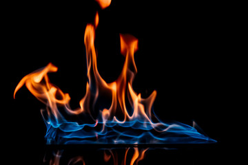 close up view of burning orange and blue flame on black background