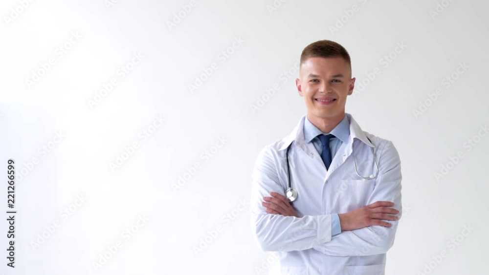 happy young doctor walking into frame and looking at camera with crossed arms on white happy young doctor walking into frame and looking at camera with crossed arms on white