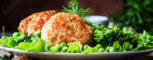 Fish cutlets or meatballs from cod and pike perch with a garnish of green peas and broccoli, rustic style, selective focus