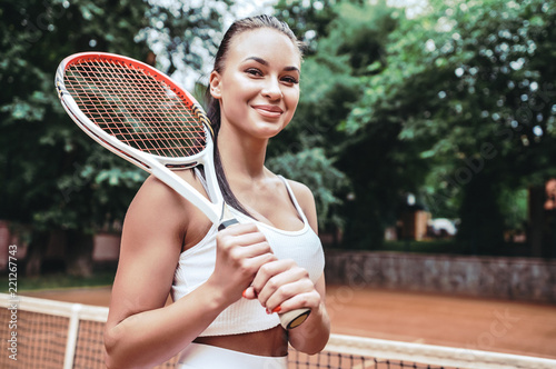 Feeling confident of winning. Beautiful young woman holding tennis racket and looking happy © HBS