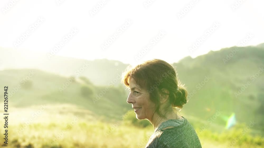 Senior woman runner walking on meadow outdoors at sunrise in nature. Senior woman runner walking on meadow outdoors at sunrise in nature.