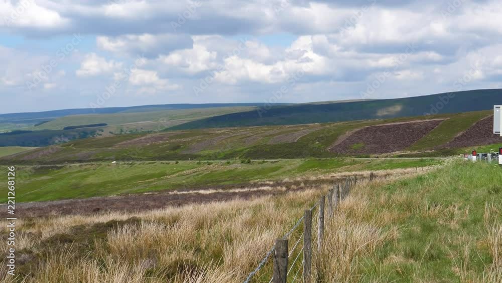 Panning shot of Peak District National Park of Pennine mountain range in England, United Kingdom. Cars and truck driving on A57 road, the Snake Pass and Glossop town in the distance in valley Panning shot of Peak District National Park of Pennine mountain range in England, United Kingdom. Cars and truck driving on A57 road, the Snake Pass and Glossop town in the distance in valley