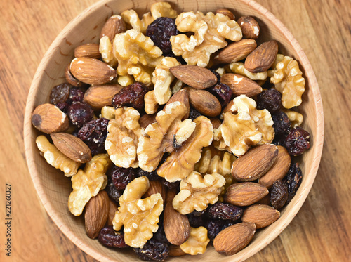 Delicious nuts arrangement in a wooden bowl. Close up shot of various nuts, healthy eating scene and wooden background. Top view.