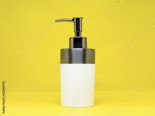 Blank white high quality hygiene liquid dispenser with metallic, reflective push hood, isolated on a yellow background