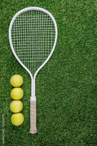 top view of tennis racket and balls of green grass