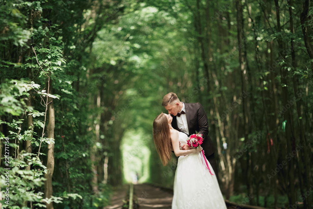 Happy wedding couple charming groom and perfect bride posing in park Happy wedding couple charming groom and perfect bride posing in park