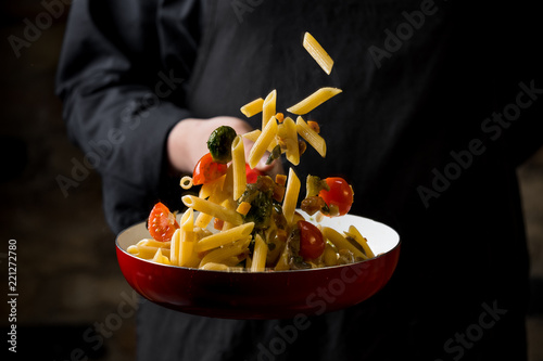 Fotografie, Obraz Cropped view of chef cooking Italian pasta with cheese, vegetables and egg yolk on hot pan flying