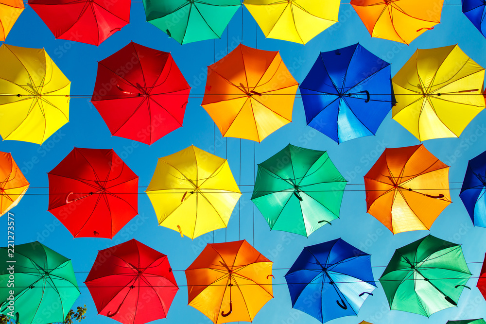 Multicolored floating umbrellas against the blue sky.
