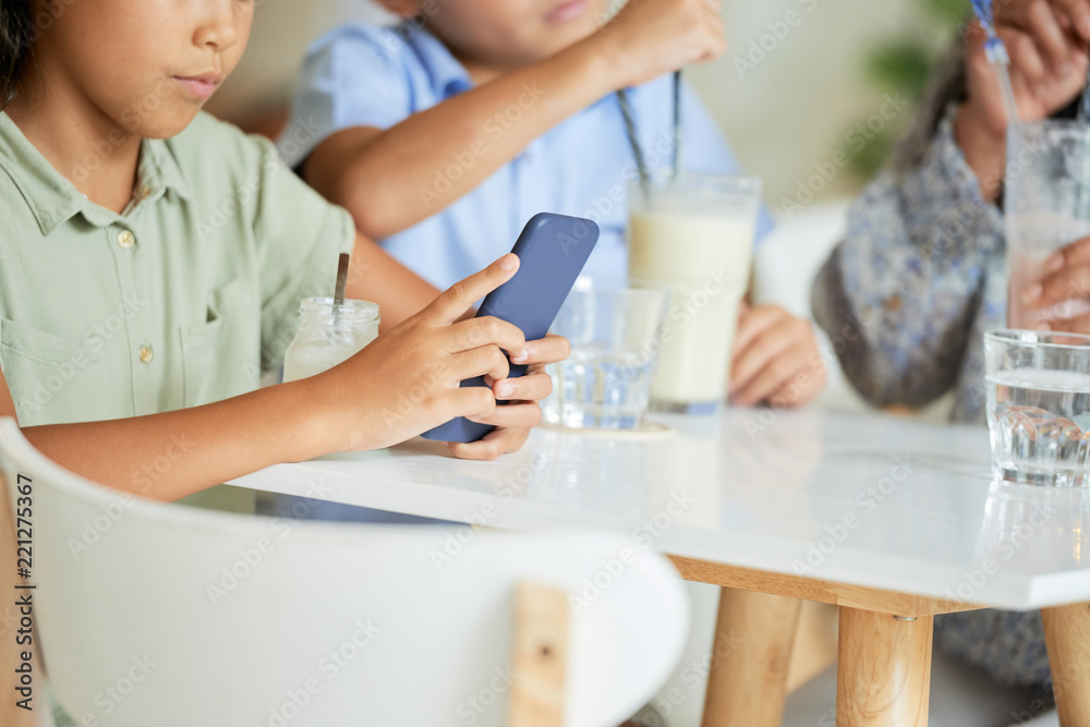 Girl using mobile app instead of talking to family at dinner in cafe Girl using mobile app instead of talking to family at dinner in cafe