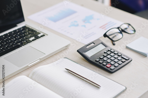 Calculator, laptop and financial report on office table