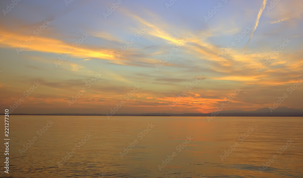 Fototapeta premium Beautiful sunset. Blurred shot of the dramatic sunset on the lake. Dramatic clouds as a defocused natural background.