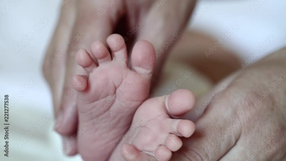 Mother hands with baby feet. One months old baby boy. Mom holds little baby feet in the hands Mother hands with baby feet. One months old baby boy. Mom holds little baby feet in the hands