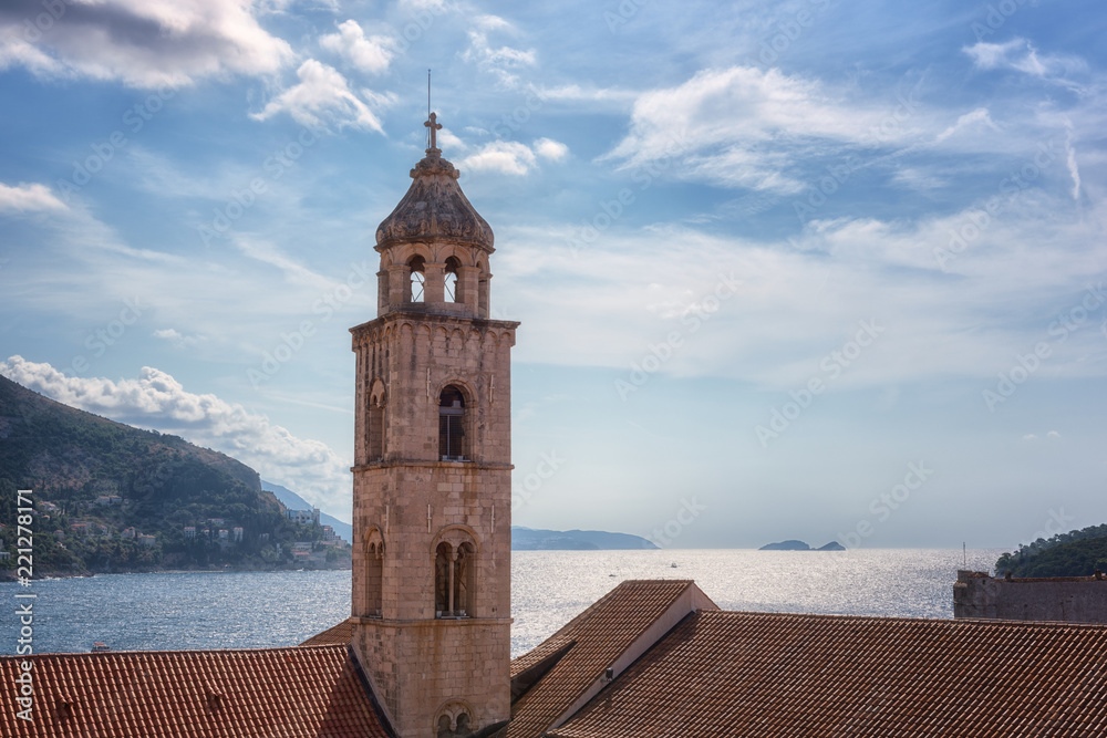 Bell tower of Dominican Monastery in Dubrovnik against beautiful blue cloudy sky and Adriatic sea. The world famous and most visited historic city of Croatia, UNESCO World Heritage site