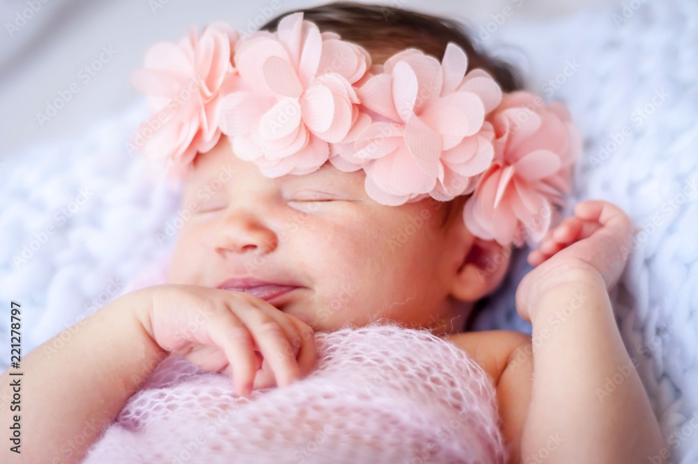 Cute sleeping newborn Caucasian baby girl a pink flower head bow. Sweet infant girl smiling in her sleep. A classical newborn infant photo session. First days of her life concept Cute sleeping newborn Caucasian baby girl a pink flower head bow. Sweet infant girl smiling in her sleep. A classical newborn infant photo session. First days of her life concept
