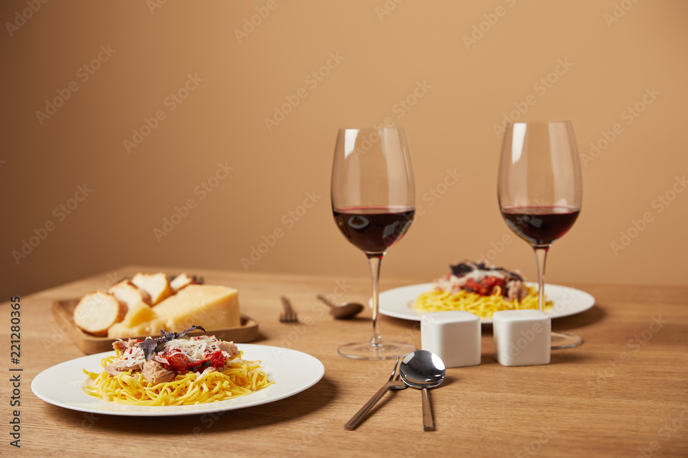 plates of delicious pasta with red wine in glasses on wooden table