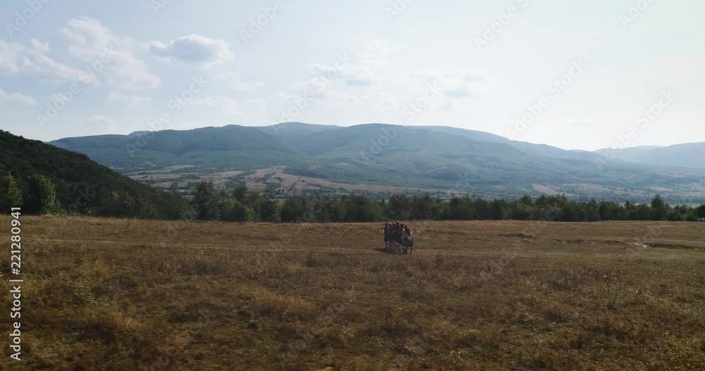 Aerial shot: Panoramic shot. A group of people in folk costumes goes up the hill Aerial shot: Panoramic shot. A group of people in folk costumes goes up the hill