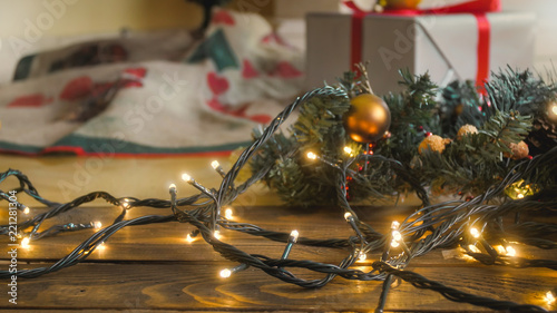 Closeup image of glowing lights garland for Christmas lying on wooden floor