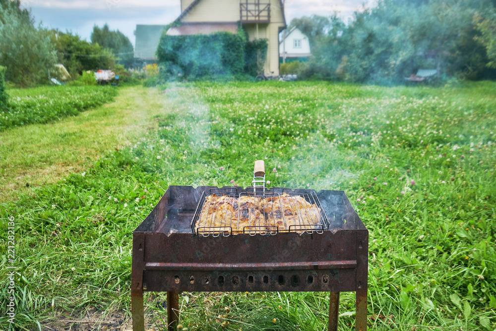 Preparing a chiken in a suburban area using a chairgrill and grill grid outdoors Preparing a chiken in a suburban area using a chairgrill and grill grid outdoors